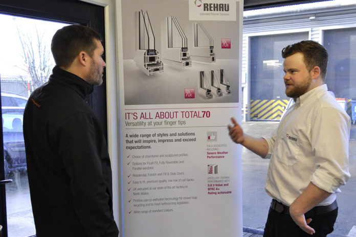 Sam Tynan discussing Rehau's Total70 product with a customer at a trade counter Sam Tynan discussing Rehau's Total70 product with a customer at a trade counter